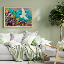 Load image into Gallery viewer, Living room with a colorful painting of a bird and flowers on the wall, a white sofa with green and white pillows, and a potted plant.