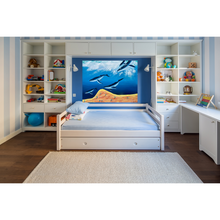 Load image into Gallery viewer, Children&#39;s bedroom with a bed, shelves, and desk in a room with striped walls and a painting of whales.
