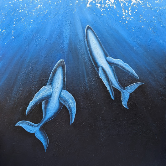 Two whales are swimming underwater with sunlight filtering through the water.